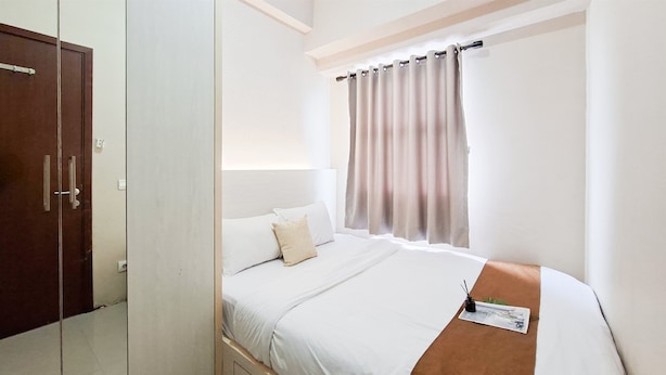 Ein Hotelzimmer mit Bett, Schrank, einem Fenster mit Vorhängen und einem Nachttisch mit Lampe.
