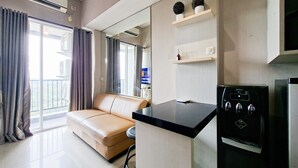 Ein modernes Wohnzimmer mit einem beigen Sofa, einer schwarzen Kücheninsel und einem eingebauten Backofen.