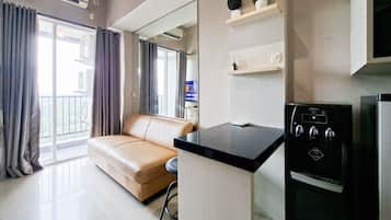 Un soggiorno moderno con un divano beige, un'isola cucina nera e un forno da incasso.