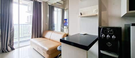 A modern living room with a beige sofa, a black kitchen island, and a built-in oven.