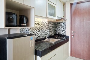 A compact kitchen with a black countertop, a stainless steel sink, and a tiled backsplash. - Comfortable Modern Look 2Br At Apartment Parkland Avenue (Tangerang)