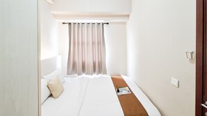Ein Schlafzimmer mit einem Bett, einem Kopfkissen, einem Nachttisch und einem Fenster mit Vorhängen.