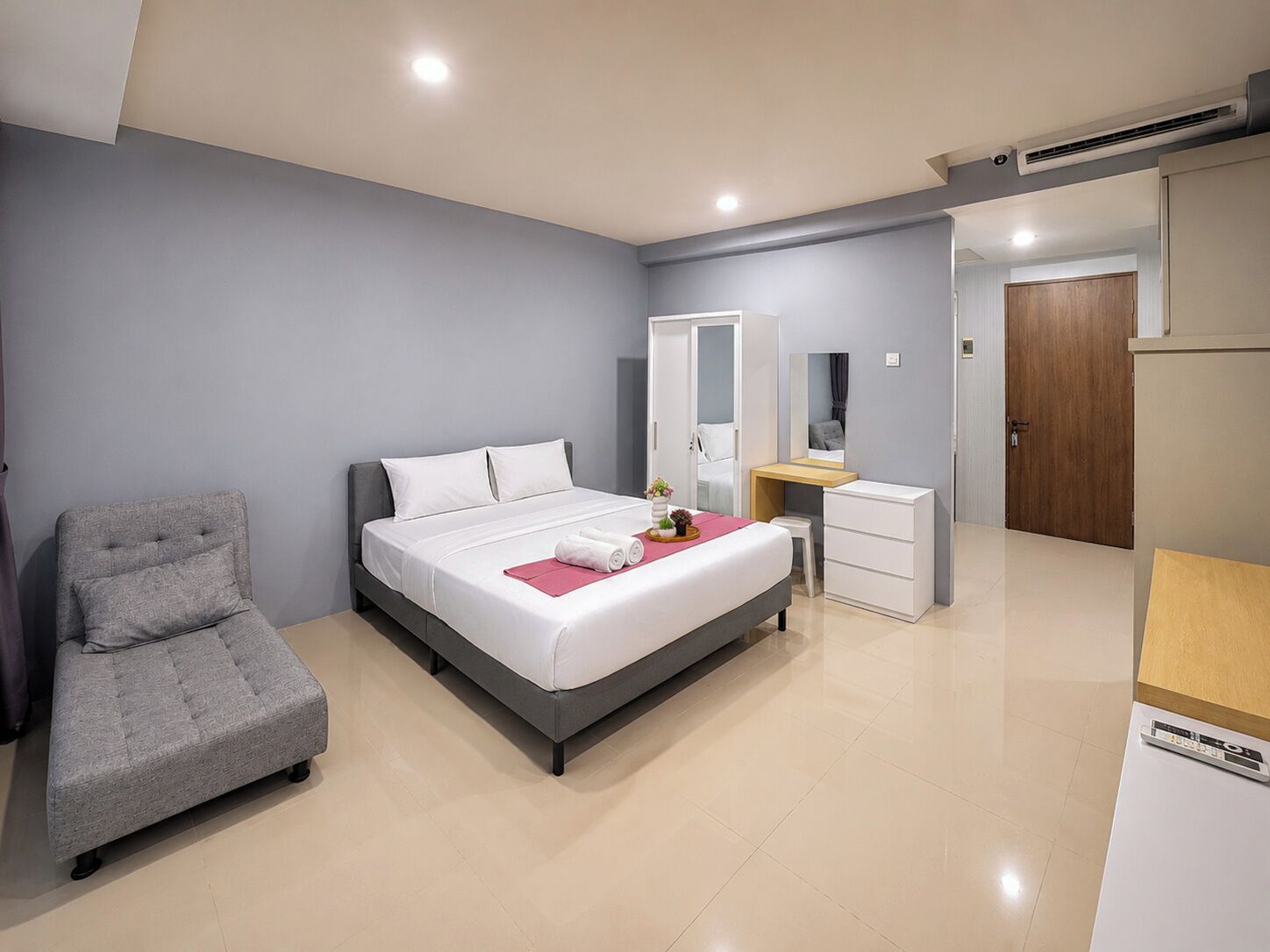 A modern bedroom with a bed, a chair, a desk, and a wardrobe.