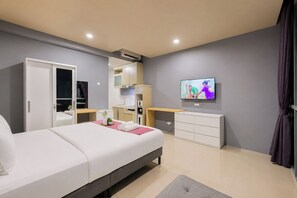 A modern hotel room with a bed, a desk, a television, and a wardrobe. - Relaxing Studio With Cityscape At Apartment The City Square Surabaya (Surabaya)