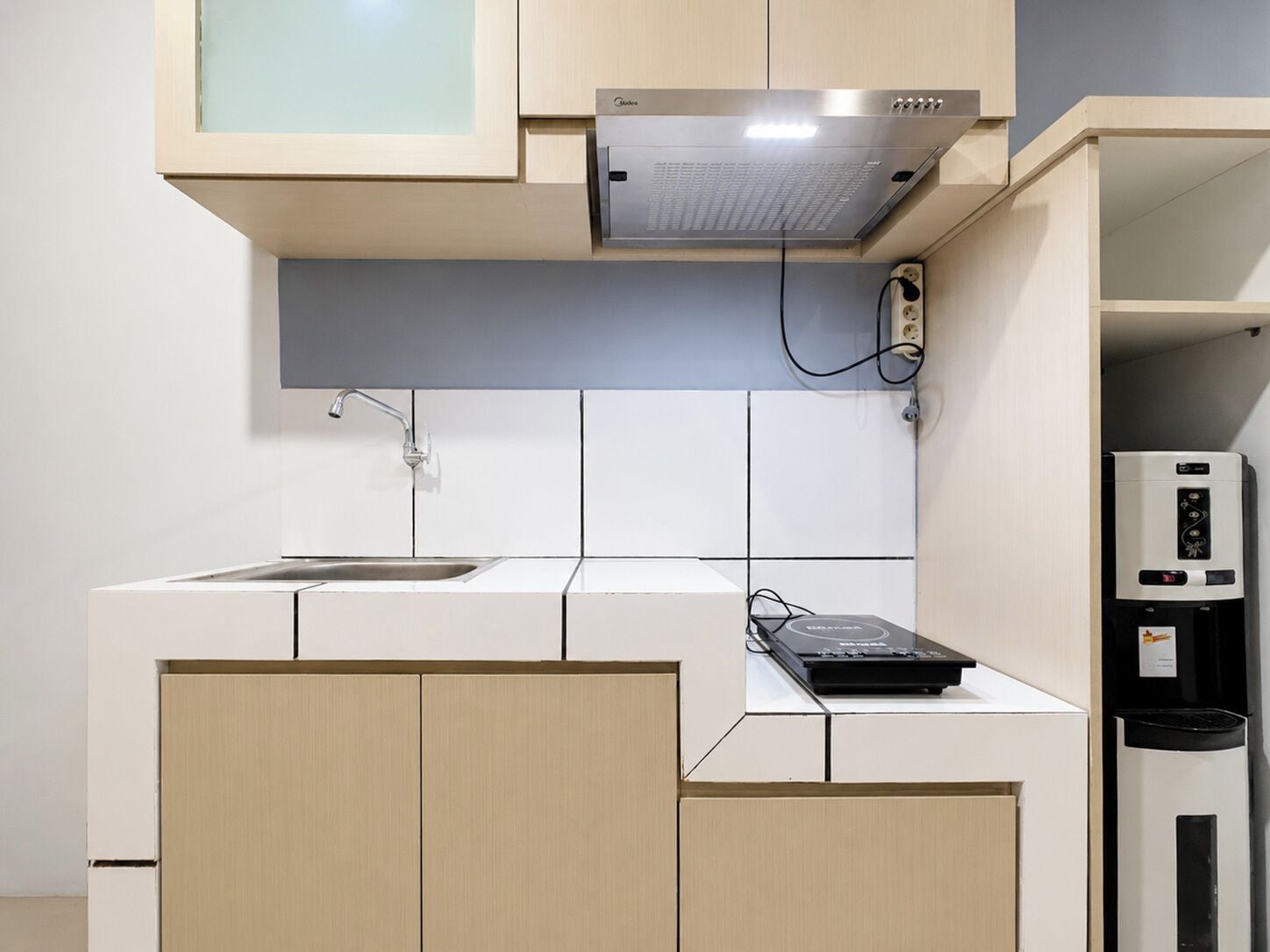 Una cocina compacta con microondas integrado, un lavabo y una cafetera.