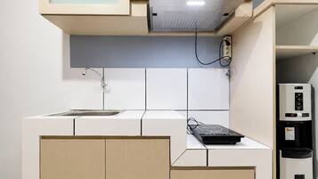 Una cocina compacta con microondas integrado, un lavabo y una cafetera.