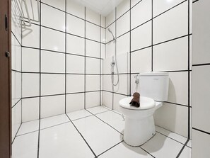 A bathroom with white tiled walls and floor, a white toilet, and a shower area. - Relaxing Studio With Cityscape At Apartment The City Square Surabaya (Surabaya)