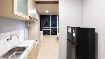 A modern kitchen with a stainless steel sink, a black refrigerator, and a city view through large windows.