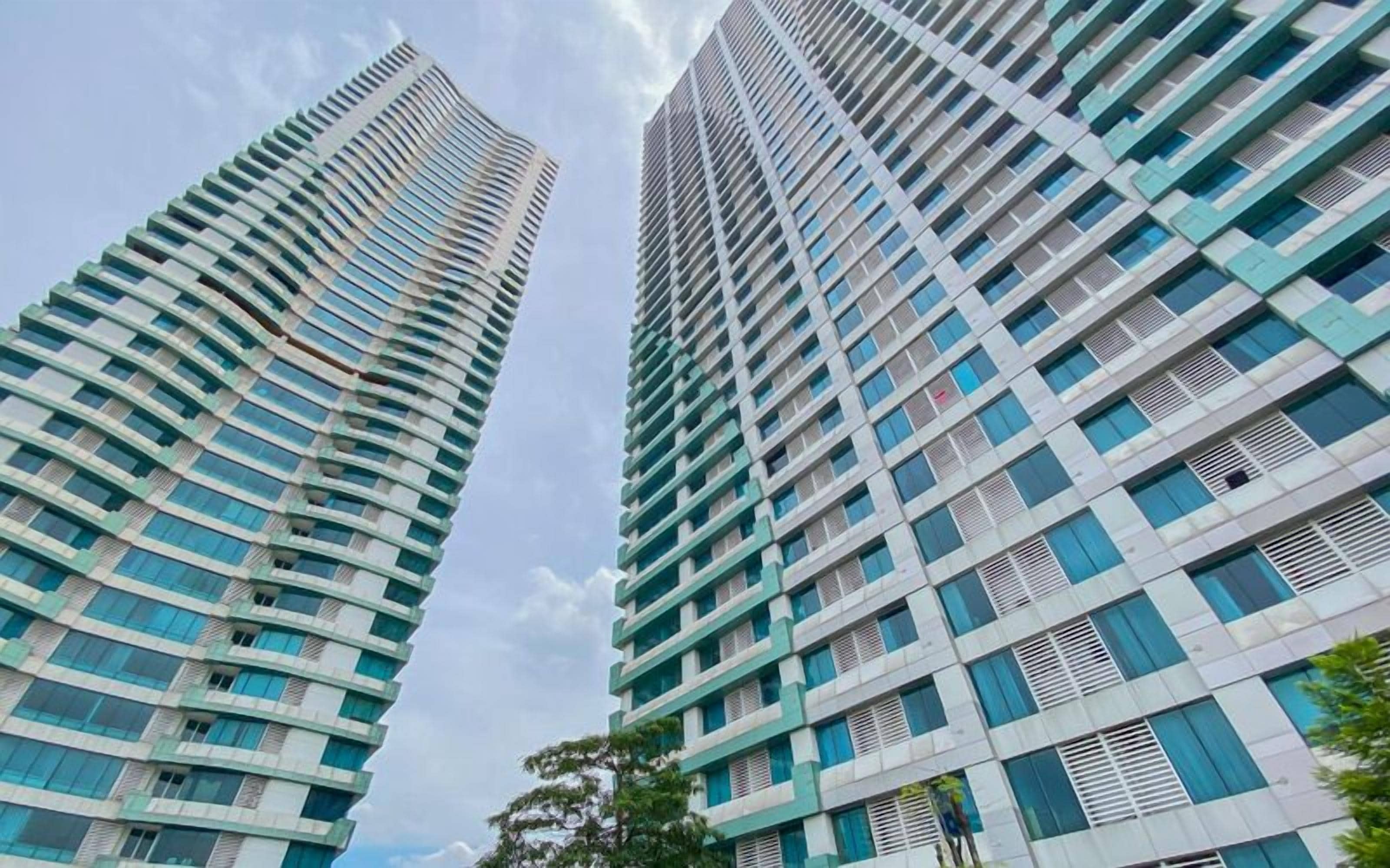 Dos edificios altos con un diseño arquitectónico moderno, que presenta una cuadrícula de ventanas y balcones.