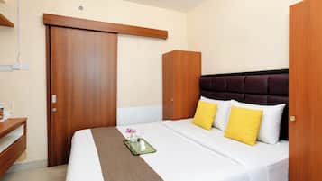 Una camera d'albergo con un letto, un comodino, un armadio e uno specchio.