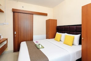 Una camera d'albergo con un letto, un comodino, un armadio e uno specchio.