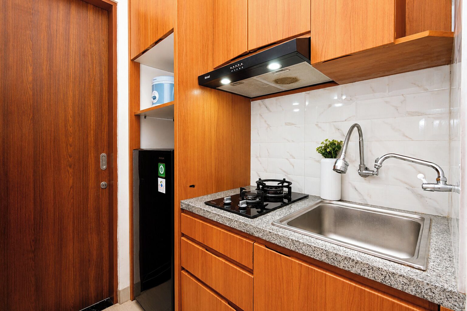 Une cuisine compacte avec des meubles en bois, un évier en acier inoxydable et une cuisinière à gaz intégrée.