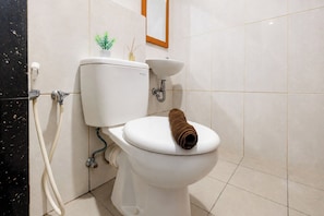 Un bagno con un asciugamano sul sedile, una piccola pianta e un portafoto appeso al muro.