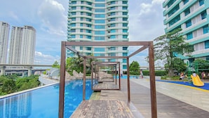 A swimming pool with wooden deck and a playground with slides. - Comfortable 1Br Without Living Room At Grand Kamala Lagoon Apartment (Bekasi)