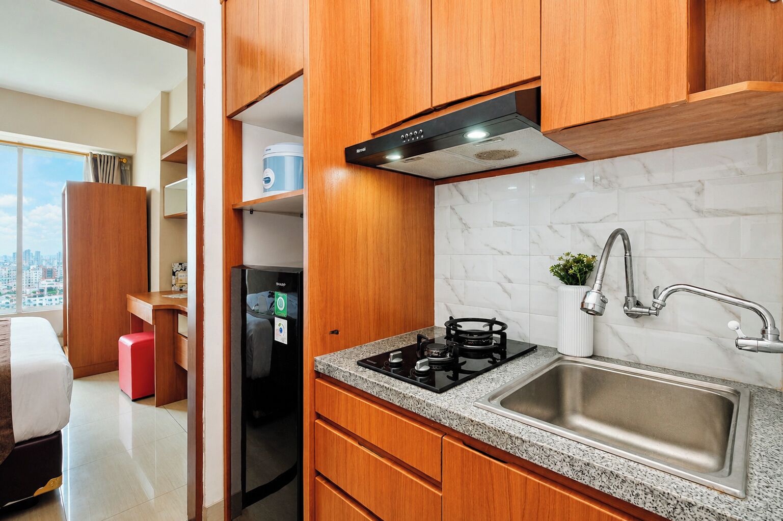 A modern kitchen with a gas stove, stainless steel sink, and wooden cabinets.