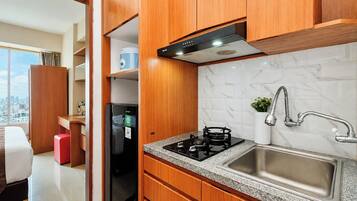 Una cocina moderna con estufa a gas, pileta de acero inoxidable y muebles de madera.