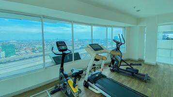 Un gimnasio con máquinas de cardio y un amplio ventanal con vista a la ciudad.