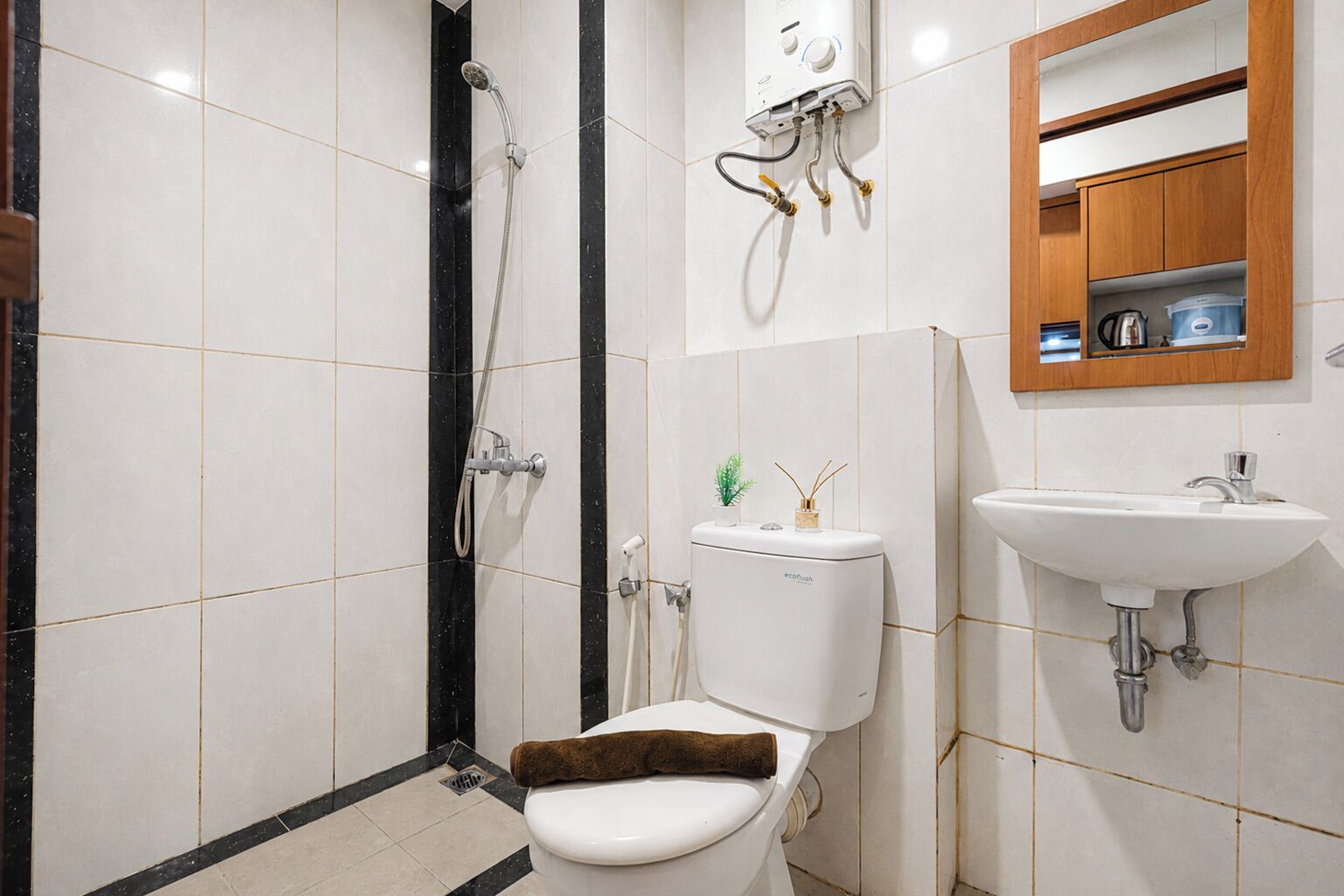 A bathroom with a toilet, shower, sink, and a mirror cabinet.