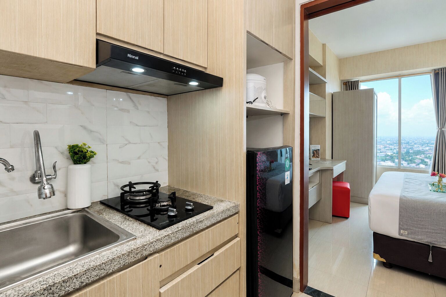 A compact kitchen with a gas stove, stainless steel sink, and a modern range hood.