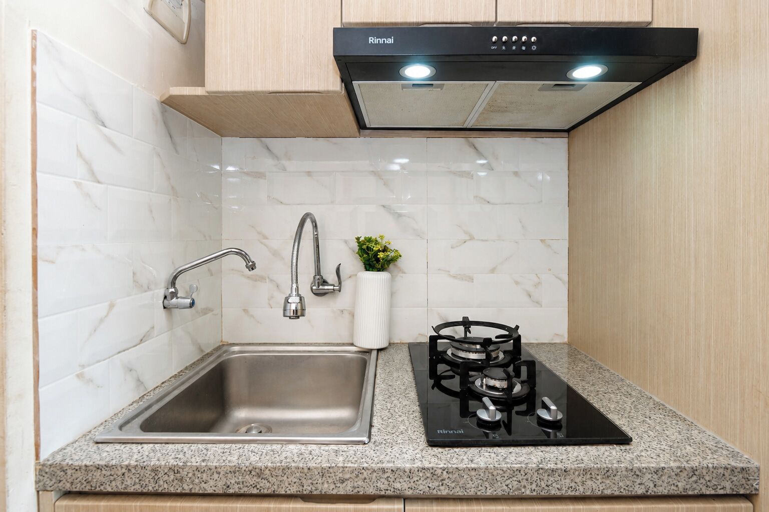 Una cocina con un lavaplatos de acero inoxidable, una estufa a gas y un extractor de humos.