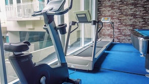 Un gimnasio con equipo de ejercicio, incluyendo una máquina elíptica, una cinta de correr y una bicicleta estática.
