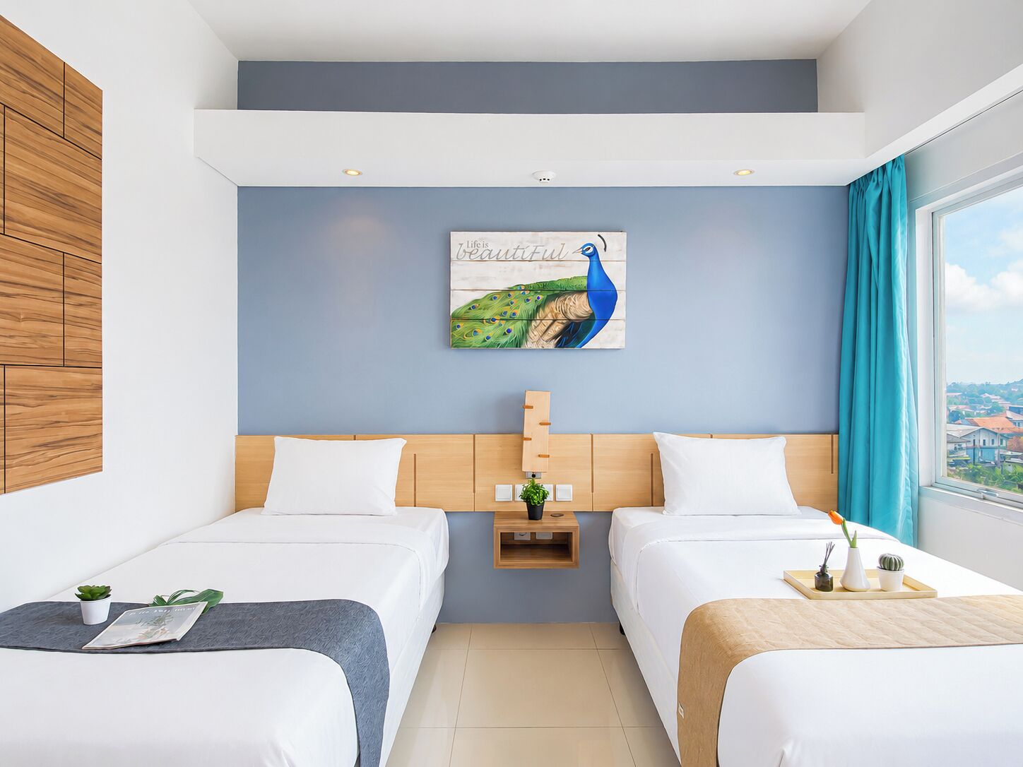 Habitación de hotel con dos camas, un cuadro de pavo real y vistas a la ciudad, con cabecero de madera.