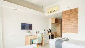 Una camera d'albergo con un letto, una scrivania con televisore, un armadio e un angolo cottura.