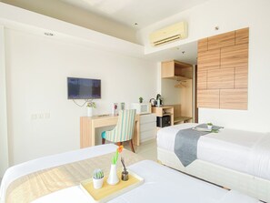 Ein Hotelzimmer mit einem Bett, einem Schreibtisch mit Fernseher, einem Kleiderschrank und einer kleinen Küchenzeile.