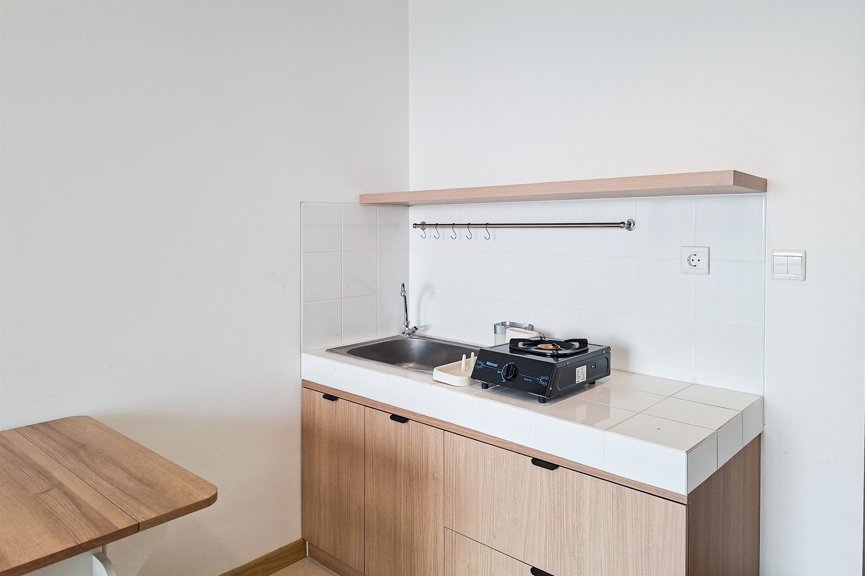 Une cuisine de taille réduite, équipée d’un évier, d’une cuisinière et de meubles de rangement en bois.