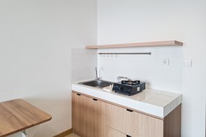 Cozinha compacta com pia, fogão e armários de madeira.