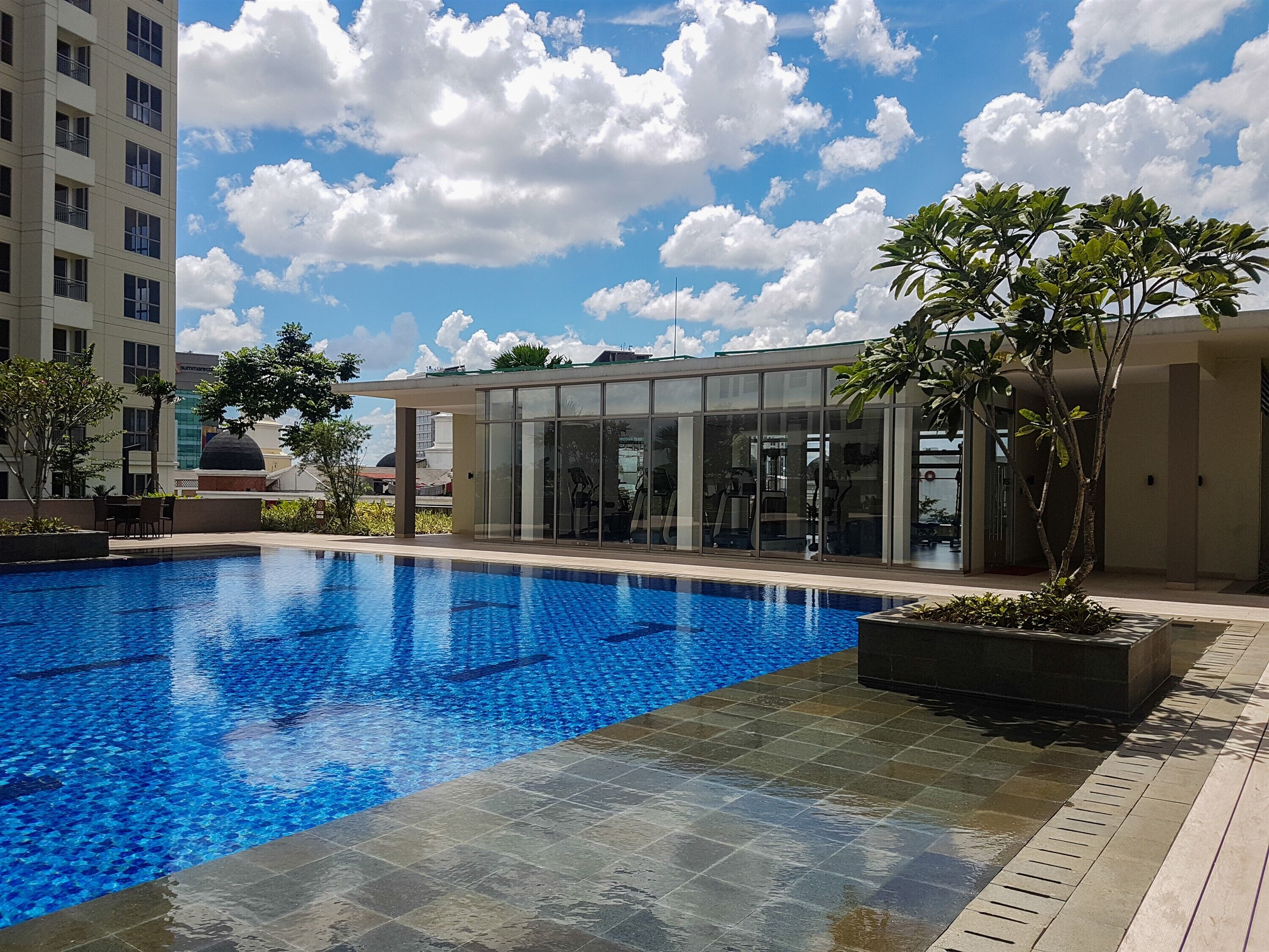 A swimming pool with a clear blue water surface, surrounded by a tiled deck.