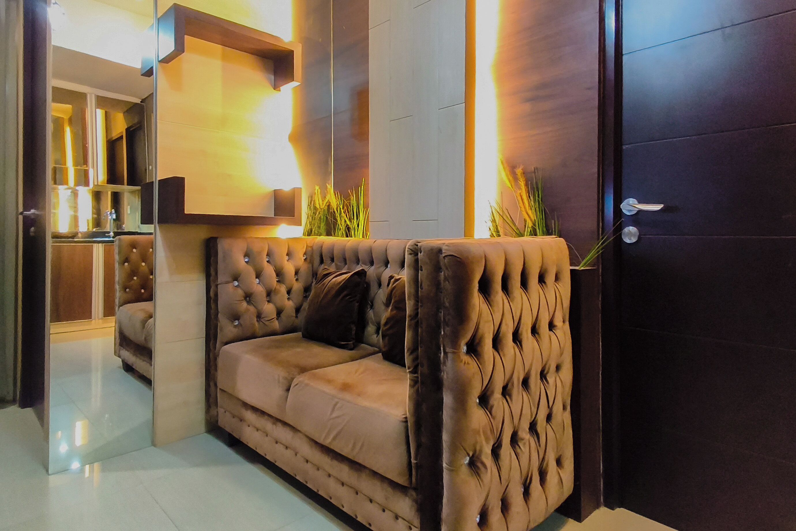 Una sala moderna con un sofá capitonado, un mueble de madera y una puerta.
