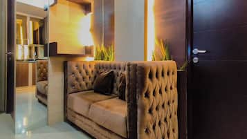 Una sala moderna con un sofá capitonado, un mueble de madera y una puerta.