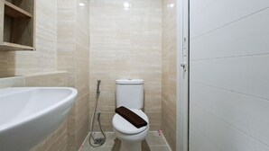 Een badkamer met een wit wastafelmeubel, toilet en douche.