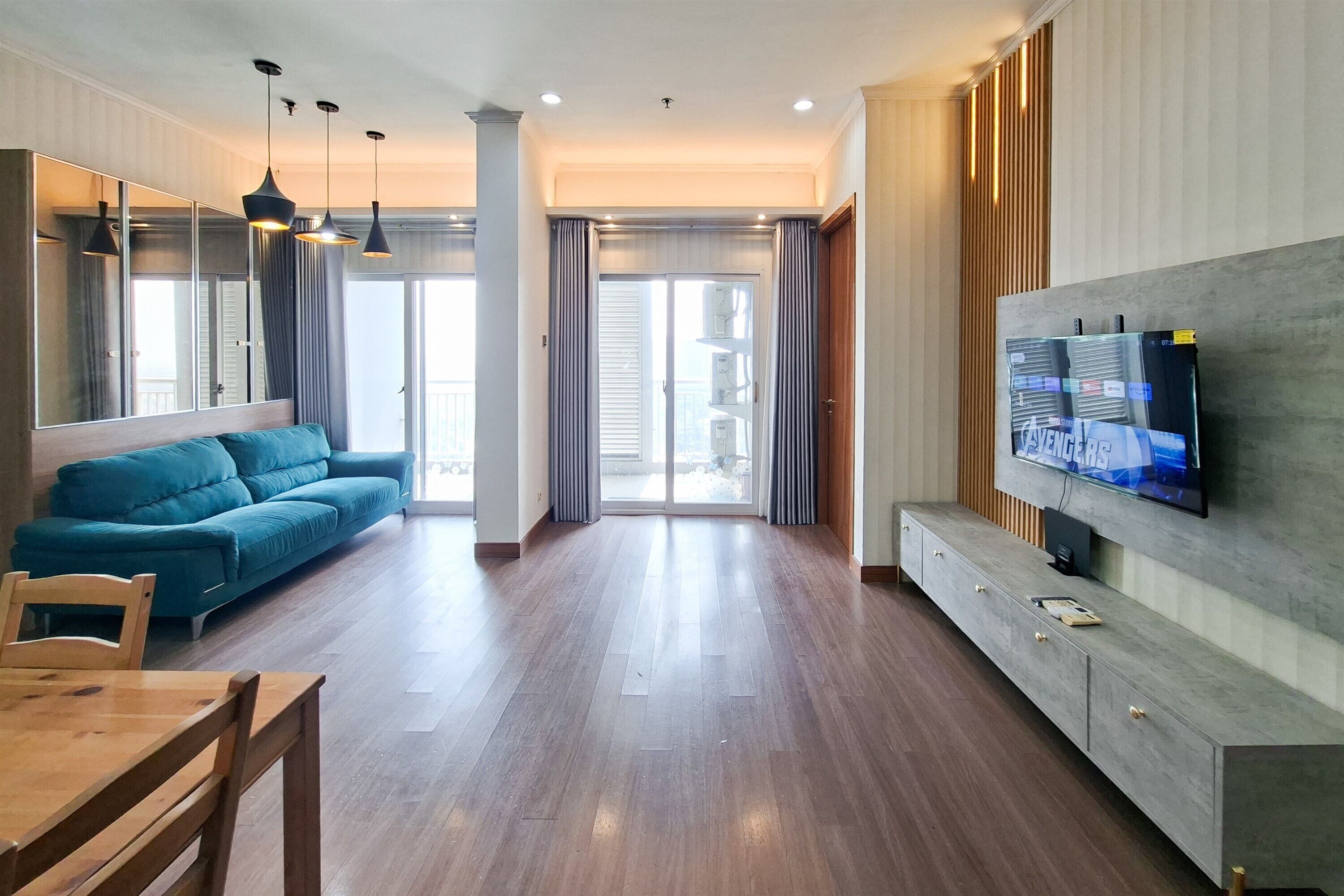 Uma sala de estar moderna com um sofá, uma TV fixada na parede e um espaço de jantar com mesa e cadeiras.