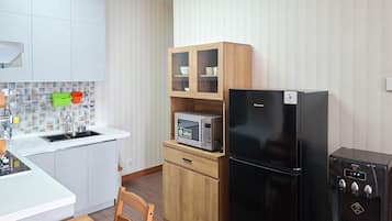 A compact kitchen with a sink, a microwave, a refrigerator, and a cabinet with glass doors.