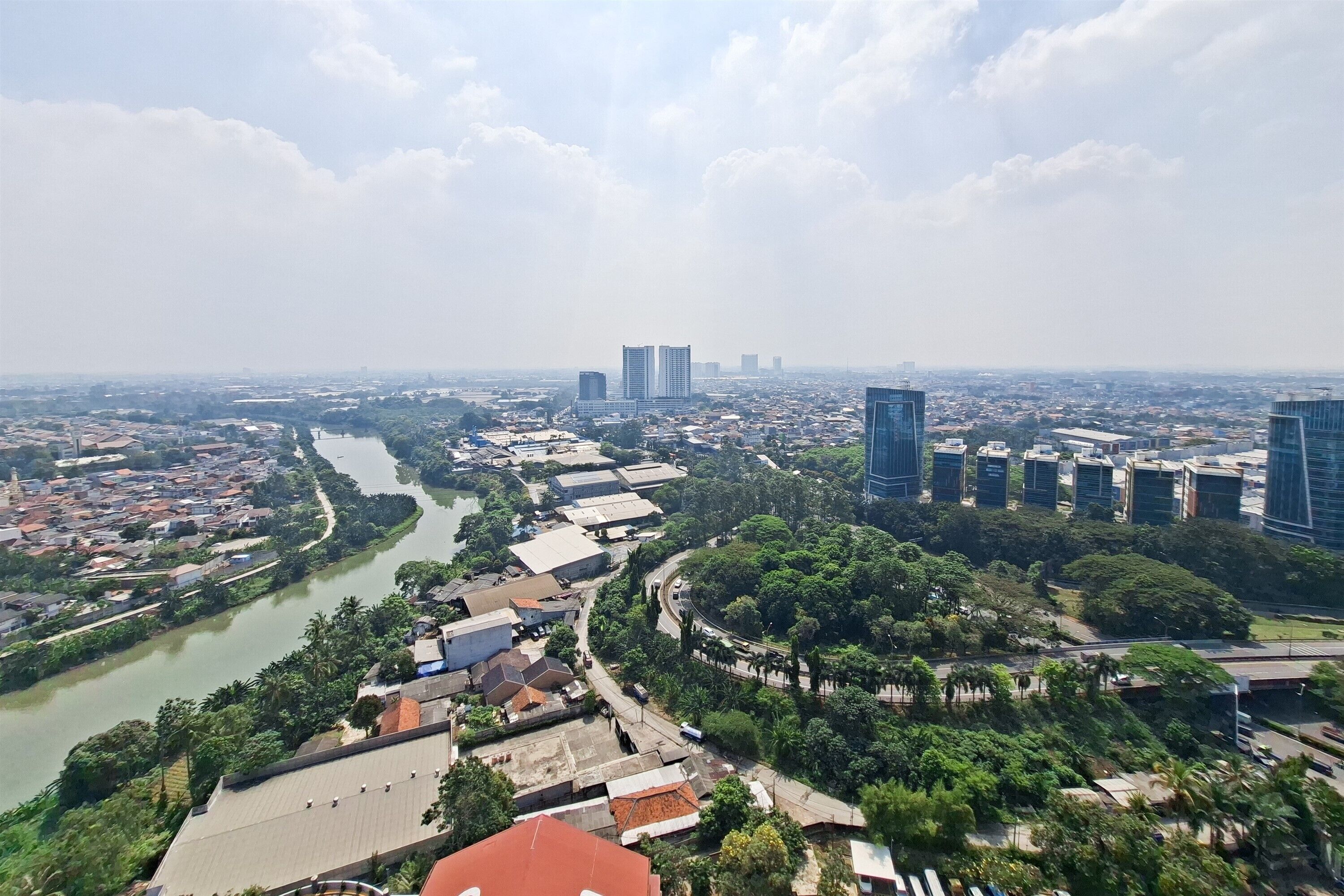 Een stadsgezicht met een rivier, gebouwen en groen.