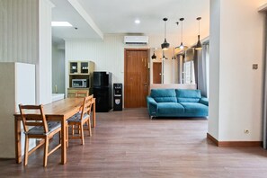 A modern kitchen with a dining table and chairs, a black refrigerator, and a blue sofa in a living area. - Comfortable 3Br Apartment At Great Western (Tangerang)