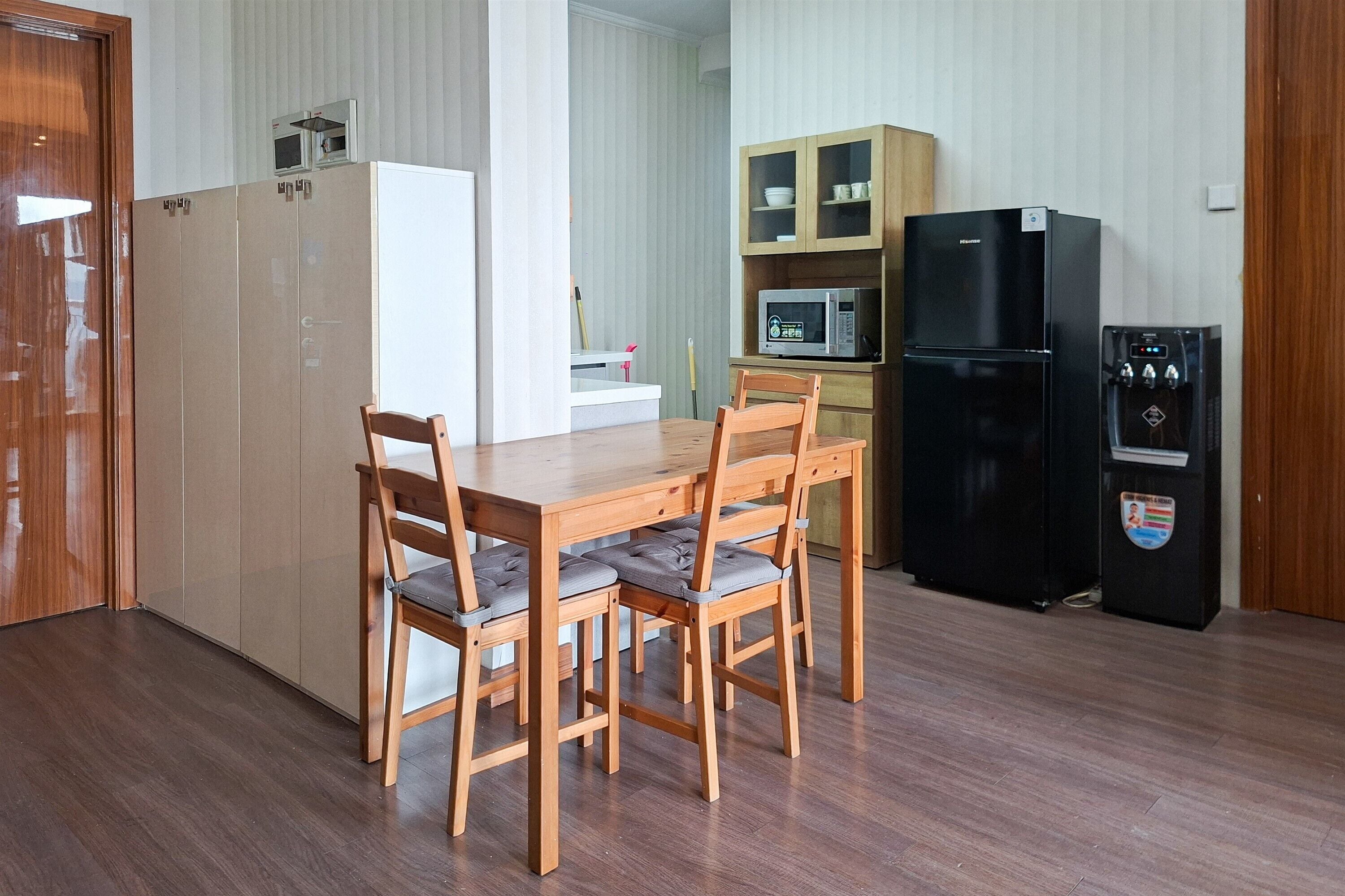 Uma cozinha compacta com mesa, cadeiras, micro-ondas, geladeira e armários.