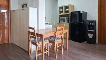 Uma cozinha compacta com mesa, cadeiras, micro-ondas, geladeira e armários.