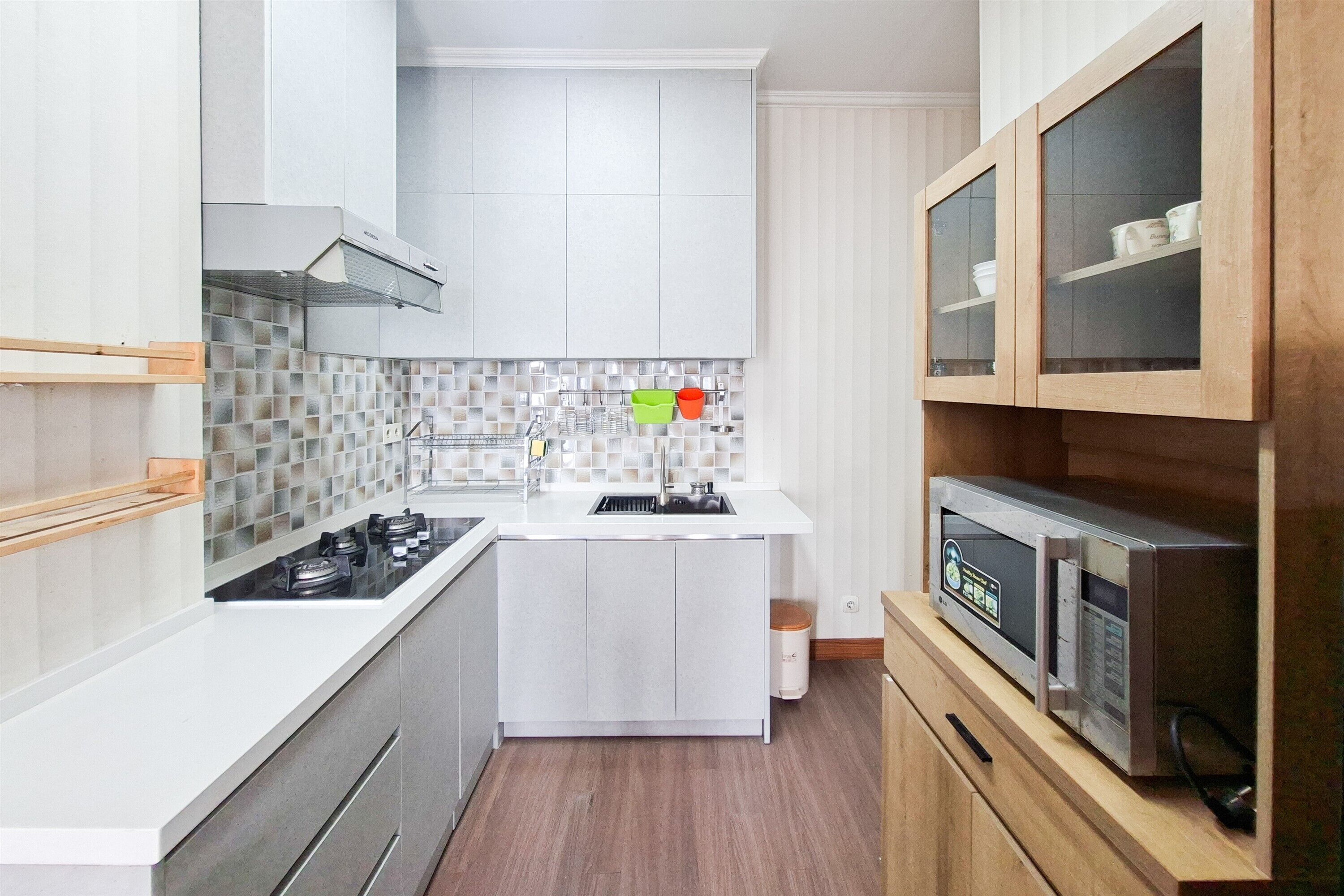 Cozinha compacta com fogão a gás, armários brancos, micro-ondas e uma pia pequena.