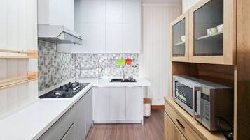 Cozinha compacta com fogão a gás, armários brancos, micro-ondas e uma pia pequena.