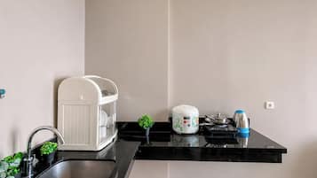A kitchen with a sink, a rice cooker, a kettle, and a small potted plant.