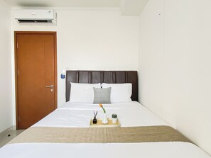 Ein Hotelzimmer mit einem Bett, einer Holztür und einer Klimaanlage.
