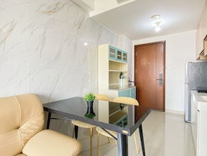 A modern kitchen with a marble backsplash, a dining table with chairs, and a refrigerator. - Comfortable 2Br At Apartment Signature Park Grande (Jakarta)