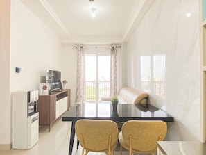 Ein kompakter Wohnraum mit Essbereich, einer Küchenzeile und einem Balkon mit Blick.