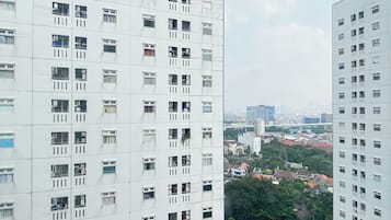 Un edificio alto con múltiples ventanas y balcones, rodeado de otros edificios y vegetación.