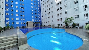 Una piscina con gradini in ceramica che vi conducono, circondata da un edificio con numerose finestre e balconi.