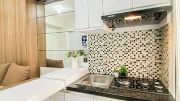 Una cocina moderna con encimera negra, pileta de acero inoxidable y cocina a gas.