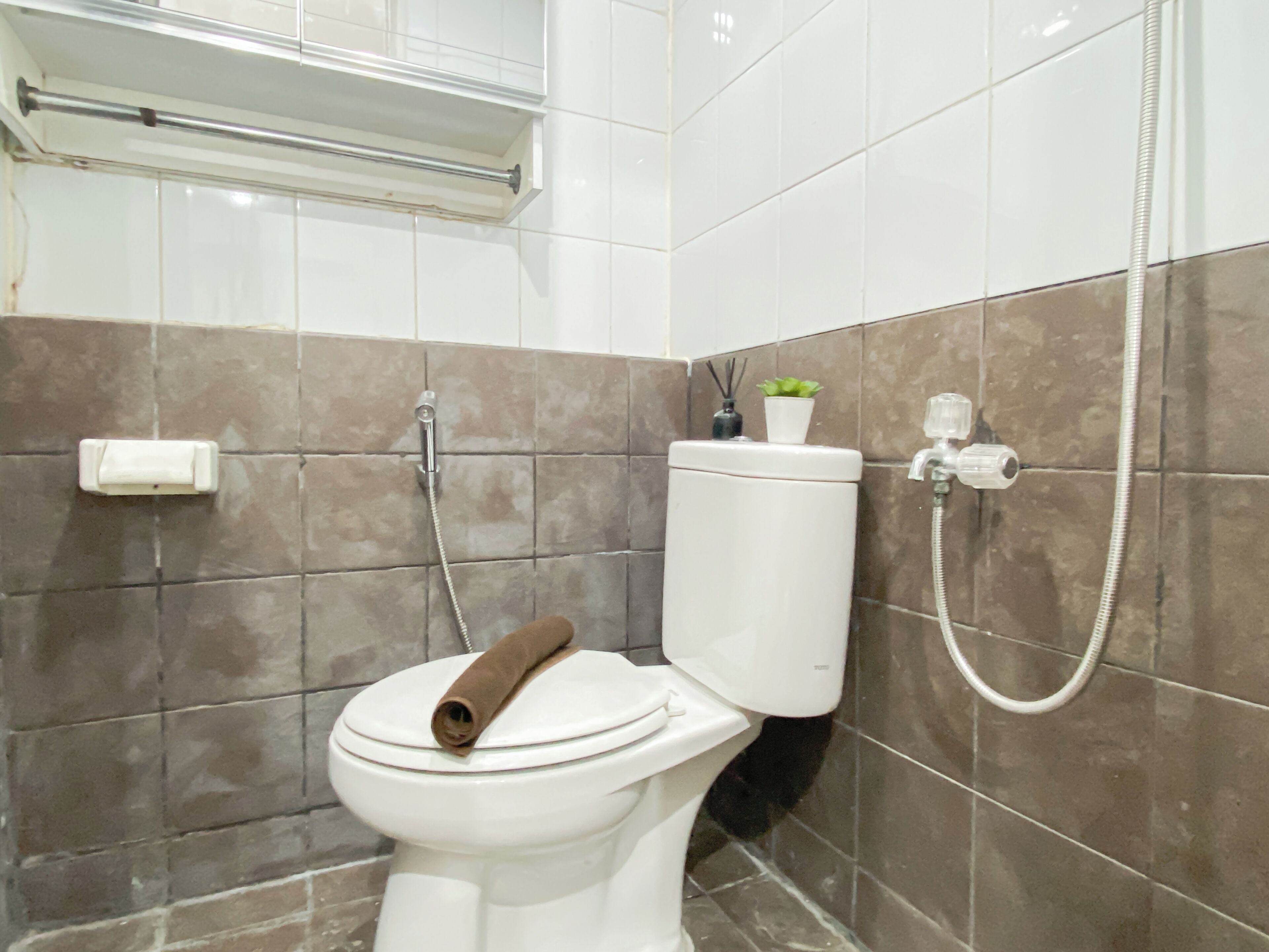 A bathroom with a toilet, a shower, and a towel rack.